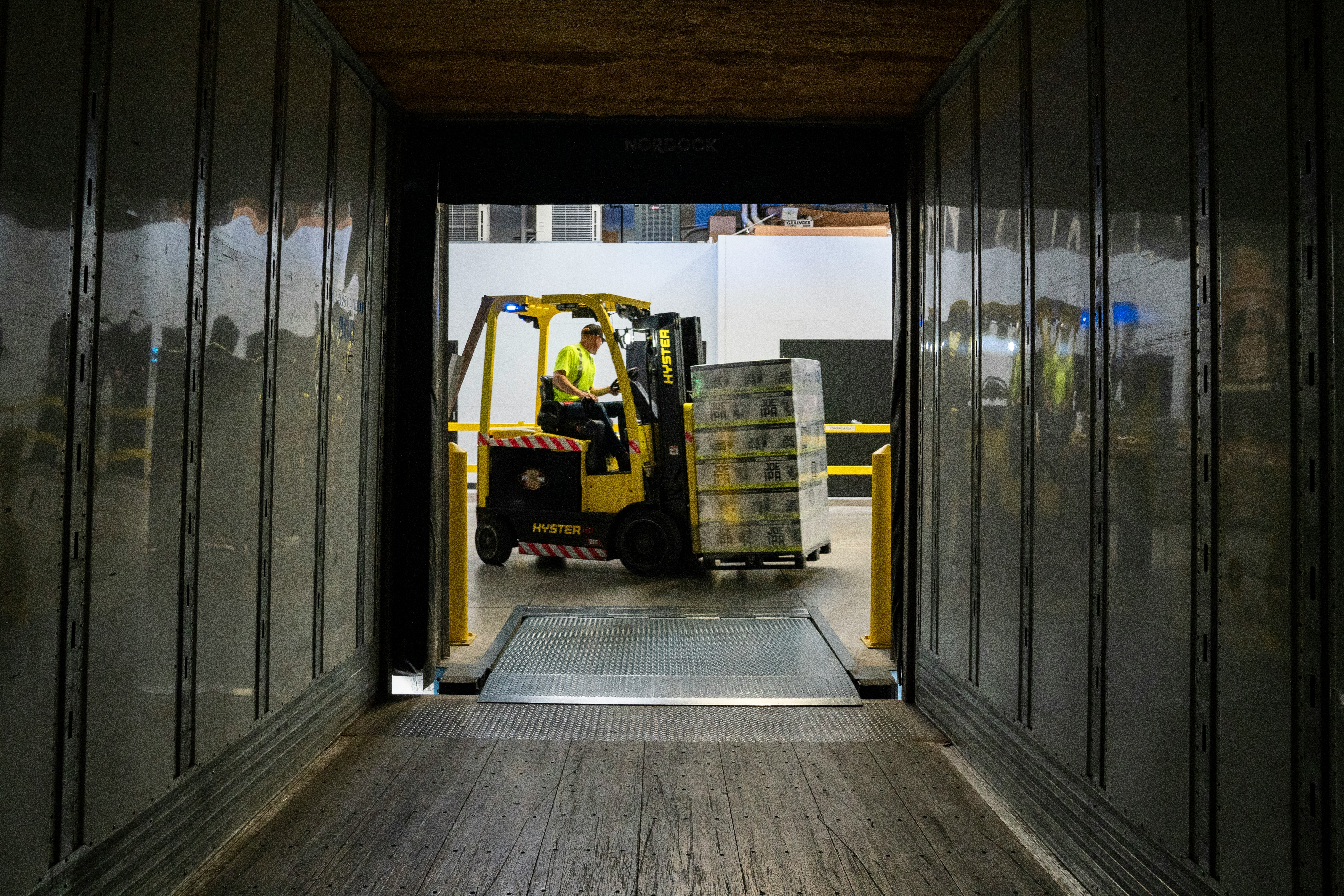 Empilhadeira carregando pallets dentro de baú de caminhão em operação industrial